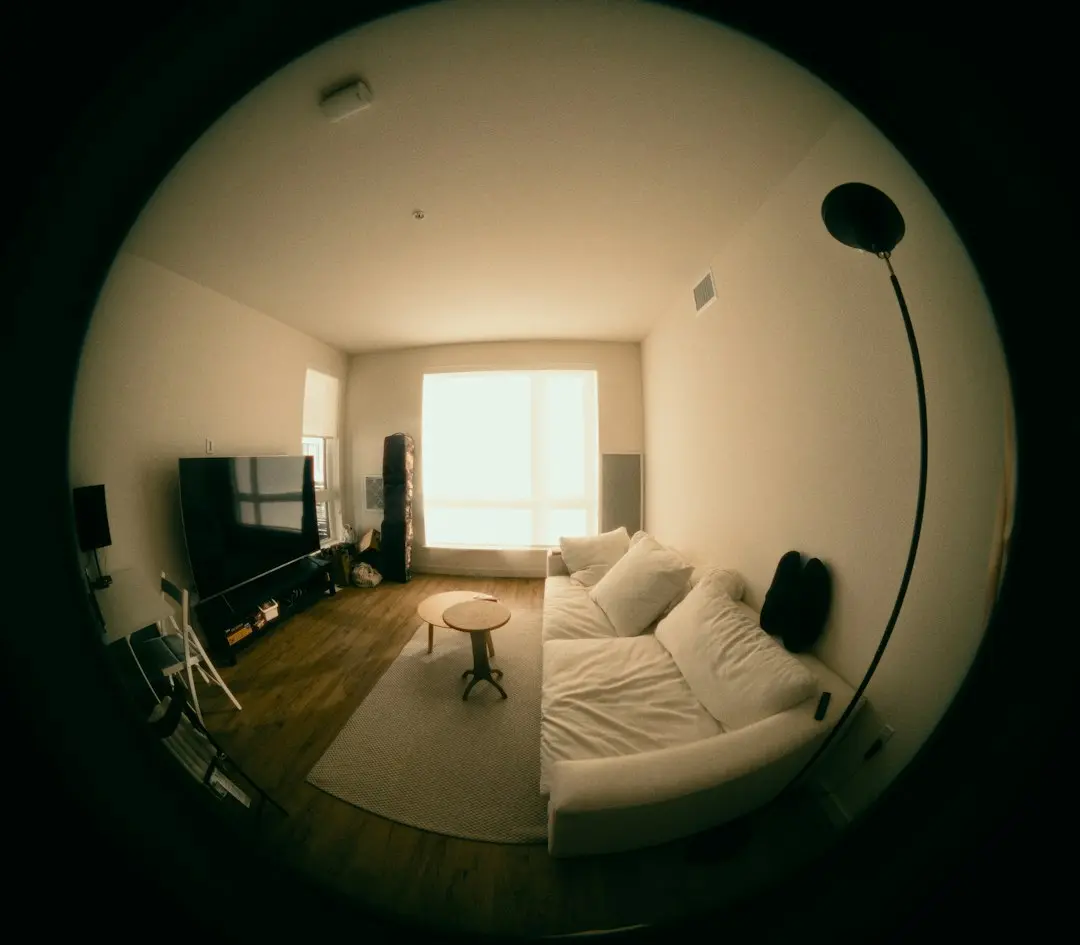 A wide-angle view of a living room with a TV and a white sofa, where Lux IPTV is watched